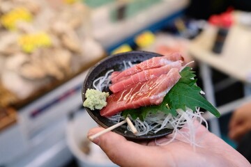 Fatty tuna sashimi slices glazed with soy sauce, and garnished with a perilla leaf and fresh...
