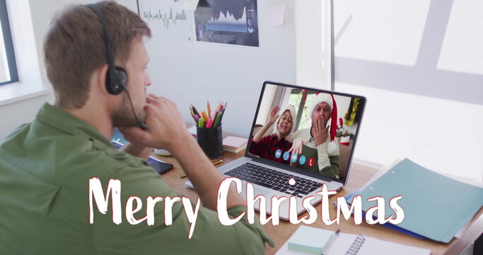 Image of merry christmas text over diverse couple on laptop screen at christmas