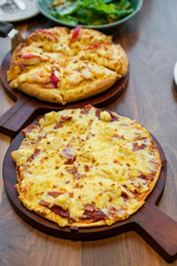 thin crispy hawaiian pizza and seafood pizza dough thick with soft cheese dual on wooden tray and table with vegetable salad for fast food cuisine to family eating at Italian restaurant and vertical
