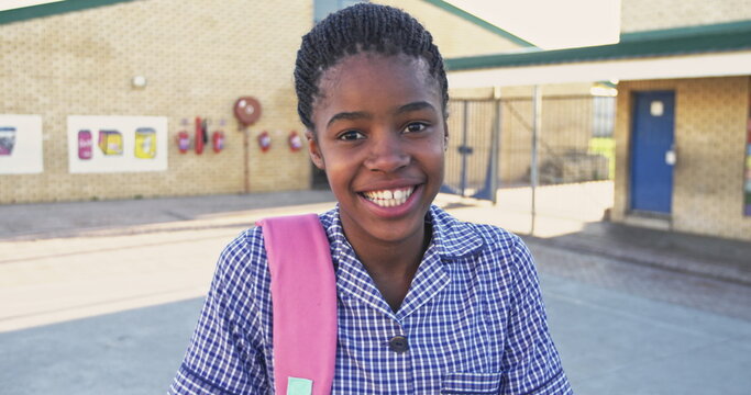Portrait close up of a young African schoolgirl wearing her school uniform and schoolbag, looking to