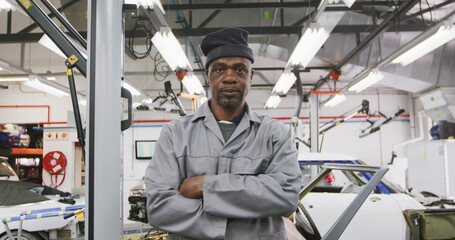 Portrait of an African American male car mechanic working in a township workshop, crossing his arms