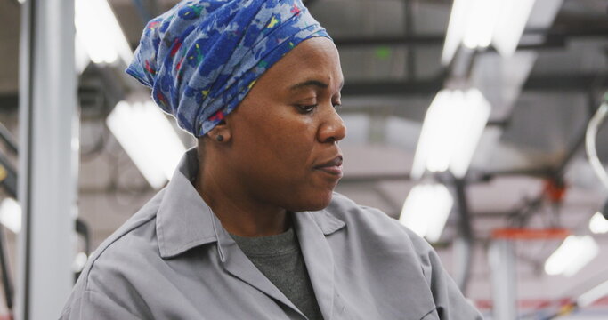 African American female car mechanic working in a township workshop, painting a body of a car in slo