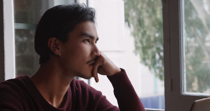 Front view close up of biracial man with short dark hair, working at home, sitting at the table in h