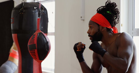 Focused ale boxer practicing boxing in fitness studio