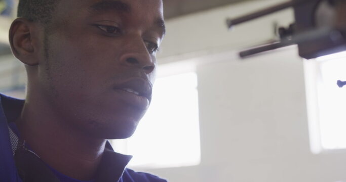 Side view close up of an African American man working at a factory making cricket balls, operating a - Powered by Adobe