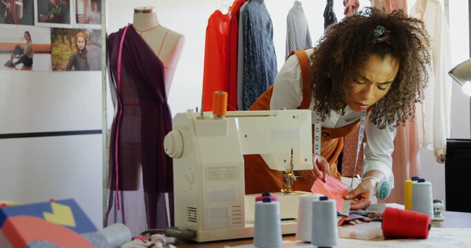 Front view of African American female fashion designer looking at cloth samples in workshop