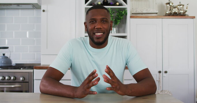 African american man looking to camera talking on image call in kitchen