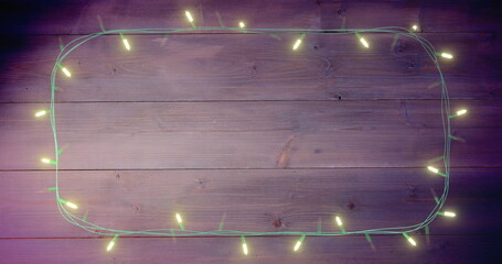 Image of flickering fairy lights with copy space on wooden background