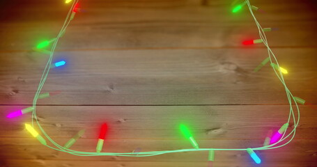 Image of flickering fairy lights with copy space on wooden background