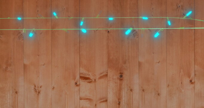 Image of flickering fairy lights over wooden background - Powered by Adobe