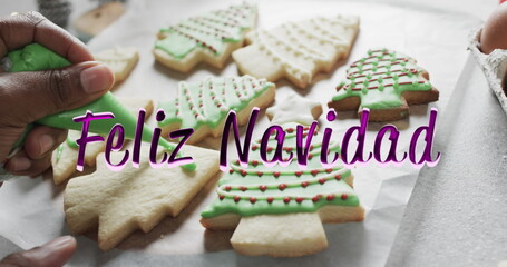Feliz navidad text in purple over african american hand decorating christmas cookies