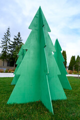 Forest of green plywood Christmas trees set on a green lawn in an outdoor park on a sunny winter...
