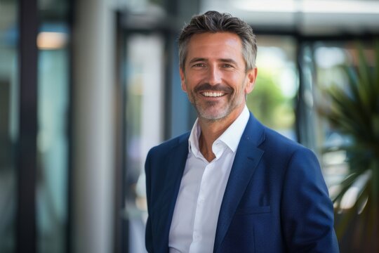 Headshot close up portrait of indian or latin confident mature good looking middle age leader, ceo male businessman in suit on office background. Handsome hispanic senior business man smile at camera