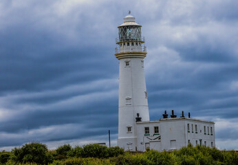 Flamborough, Yorkshire, United Kingdom - 18 July 2024: Bridlighton bay, New Flamborough lighthouse on dramatic sky.