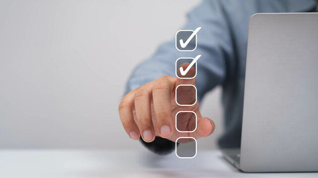 A person checking off items on a digital checklist using a laptop, symbolizing productivity and task management in a modern workspace.
