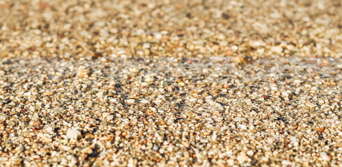 Background of sand, small pebbles and flowing wave on the sea beach. Summer vacation concept