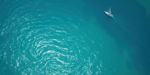 Obraz premium A lone sailboat glides across a tranquil expanse of turquoise water, its wake creating a shimmering path in the sun-dappled surface.