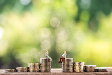 Two businessmen standing on the stack coins are negotiating for buy and sell or exchange purchase the money put on the wood in the public park, Loan and investment for planning concept.