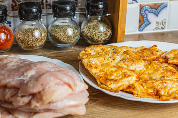 the process of cooking chicken chops with already fried chops in the background