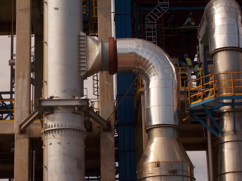  Industrial pipes and chimneys with metallic finish in a construction setting, highlighting engineering precision and structure.