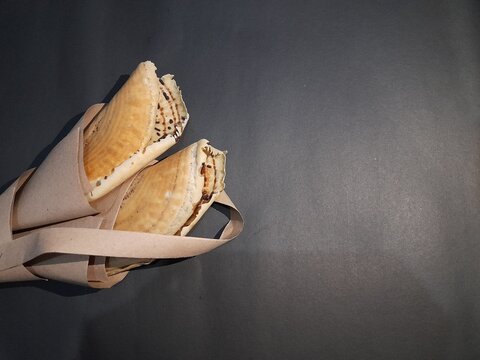 Leker cake wrapped in brown paper with a black background in the morning. background concept of traditional snacks, healthy food, homemade, handmade, breakfast, cooking, food recipes, home business