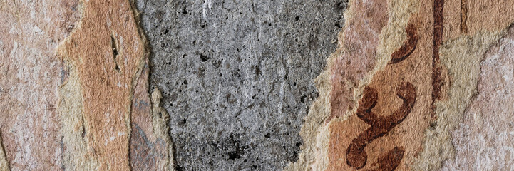 Torn old faded paper wallpaper with a retro pattern. Tattered scraps of paper on a concrete wall. Vintage texture for background and design. Closeup view with copy space.