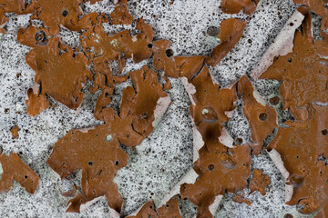 Brown peeling paint on the wall. Old concrete wall with cracked flaking paint. Weathered rough...