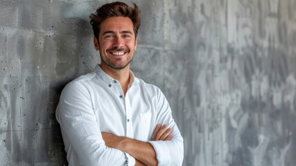 Obraz premium Confident Young Man Smiling in White Shirt Standing Against an Industrial Concrete Wall Background