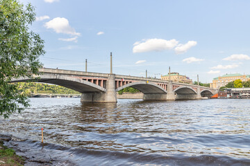 Fototapeta premium View from embankment of the Manes Bridge and the opposite embankment on Vltava River in Prague in Czech Republic