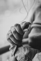 Black and white close up of mother's hand holding baby's hand