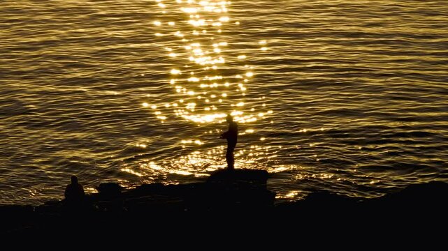 Man Fishing In The Ocean During Sunset