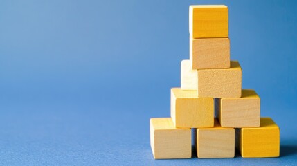 Business growth concept with yellow wooden cubes stacked on a blue background symbolizing strategic planning and enterprise resource planning.
