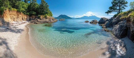 Obraz premium Serene panoramic view of a tranquil beach with crystal clear waters and lush greenery on a sunny day.