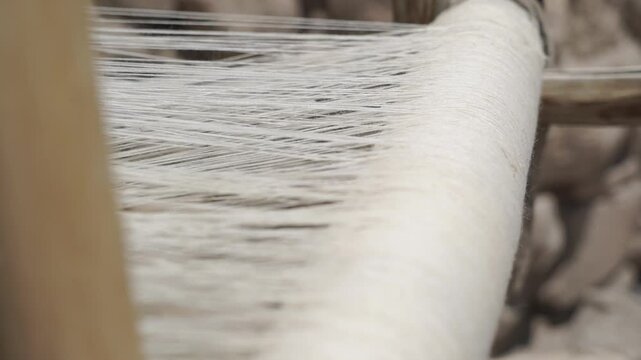 old antique traditional wooden loom weaving fabric by passing thread through warp and weft threads in  Ladakh, India