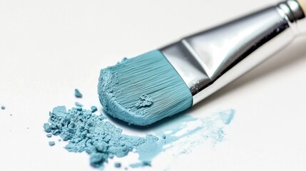 Aquamarine paintbrush with a smear and powder on a white background showcasing artistic creativity and color texture.
