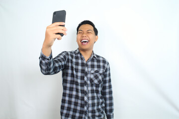 cheerful asian man laughing chatting on smartphone wearing casual shirt isolated on white, joyful male texting on cell phone