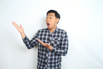 Naklejka premium shocked asian man presenting hand with disbelief face expression wearing casual shirt isolated on white