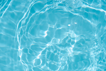 Blue water with ripples on the surface. Defocus blurred transparent blue colored clear calm water surface texture with splashes and bubbles. Water waves with shining pattern texture background.