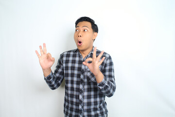 funny asian man showing okay symbol using hand with surprised and shocked expression isolated on white