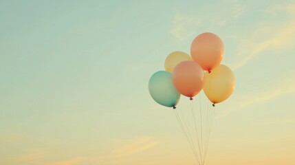 Fototapeta premium An evocative scene of a collection of diverse, multi-colored balloons rising together against a soft, pastel sky
