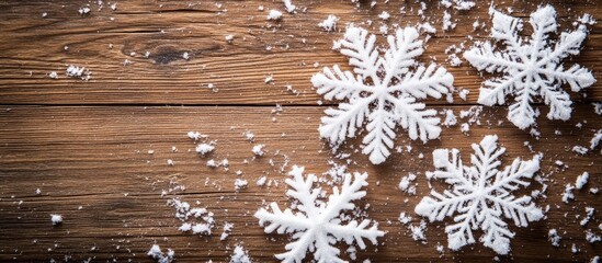 Fototapeta premium Christmas snowflake decorations on rustic wooden surface with artificial snowflakes creating a festive winter atmosphere.