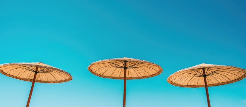 Beach umbrellas under clear blue sky creating a serene coastal atmosphere perfect for summer relaxation and outdoor leisure activities