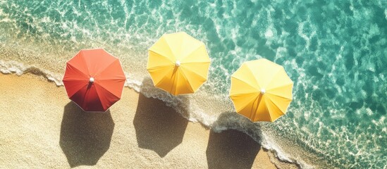 Colorful beach umbrellas on sandy shore with clear blue ocean waves creating a serene summer vacation atmosphere.