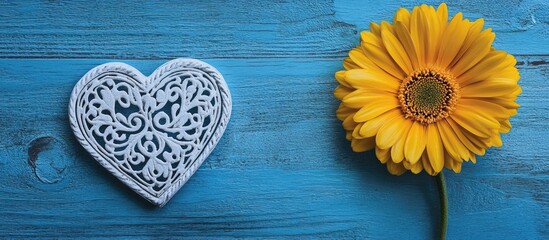 Fototapeta premium Thank you greeting card design with a vibrant yellow flower and decorative white heart on a rustic blue wooden surface.