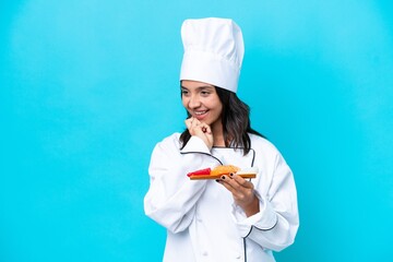 Young hispanic chef woman holding sashimi isolated on blue background looking to the side and smiling