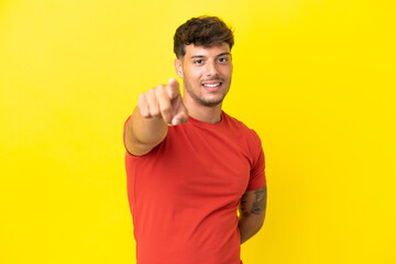 Young caucasian handsome man isolated on yellow background pointing front with happy expression