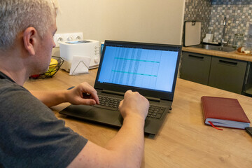 Man working on laptop on the kitchen counter top with an excel sheet on computer screen showing bank loan amortization table. Accounting