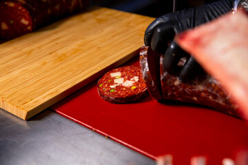Close up Butcher handscutting sausages in a butcher shop, preparing meat products for sale. Cook cuts pieces of homemade meat products.