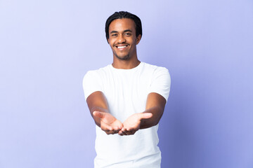 Young African American man with braids man isolated on purple background holding copyspace...
