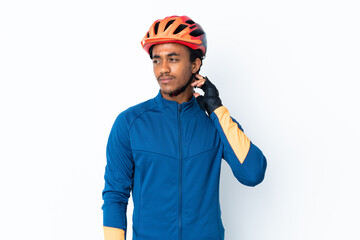 Young cyclist man with braids over isolated background having doubts